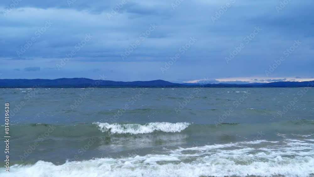 A landscape view of a freshwater lake. Strong gusts of wind and large waves near the shore. The natural landscape. A landscape view of a freshwater lake. Strong gusts of wind and large waves near the shore. The natural landscape.