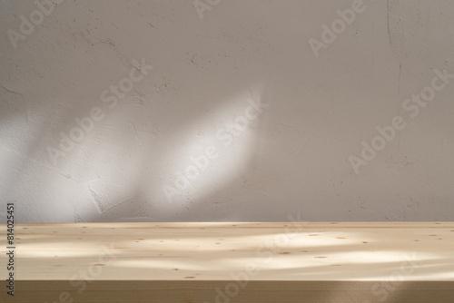 Wooden table mockup on stucco background with abstract sun light reflections on the wall. Mock up for branding products, presentation and health care.	
