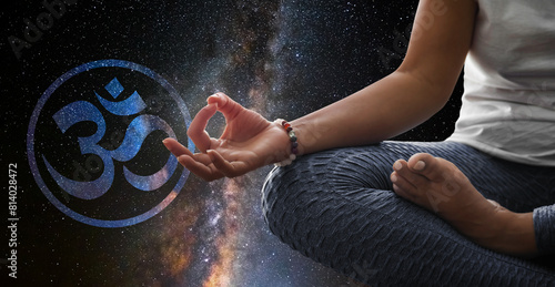 Woman meditating with the universe in the background with buddhist Om sign 