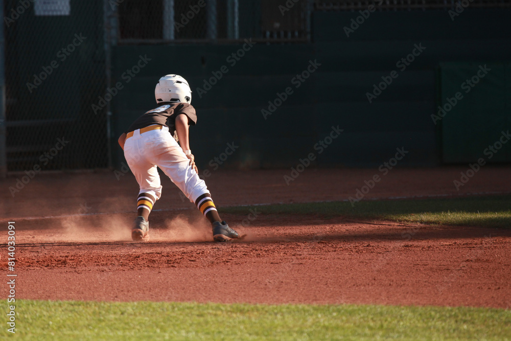 Obraz premium Youth baseball player, runner in action, baseball dust, base running, room for copy