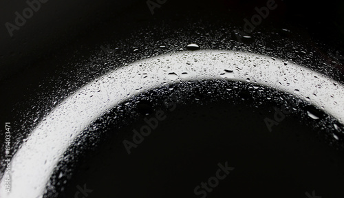 Small and large drops of water on a glass surface illuminated from below closeup view
