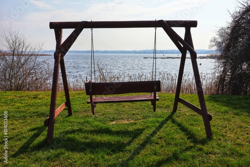 An empty swing standing on the river bank.