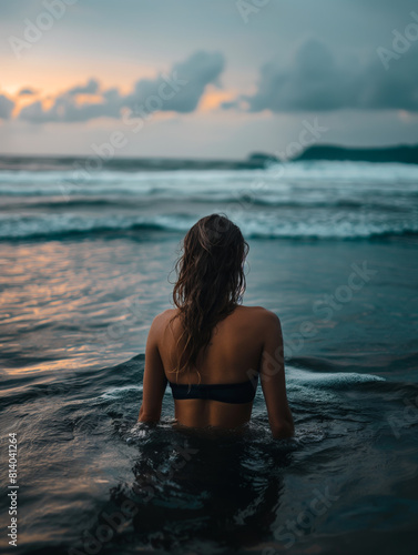 Young woman walking in the water in the soft light after sunset