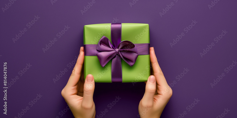 Hand hält bunten Geschenkekarton in grün mit lila Schleife Hand hält bunten Geschenkekarton in grün mit lila Schleife