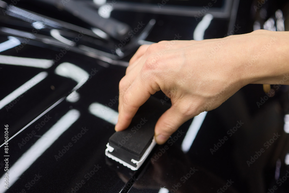 man wearing black gloves applying ceramic coating to car using sponge. Professional car detailing man wearing black gloves applying ceramic coating to car using sponge. Professional car detailing