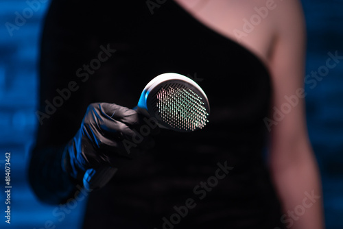 Girl in a black dress and black latex gloves holds Deshedder in her hands.  Brush for combing wool.  Slicker. Comber for animals.  Grooming tool for dogs and cats photo