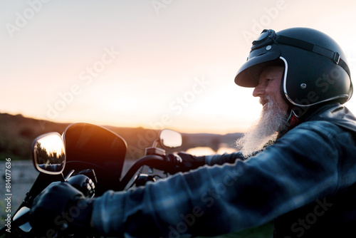 Senior man enjoying a sunset ride on his motorcycle photo