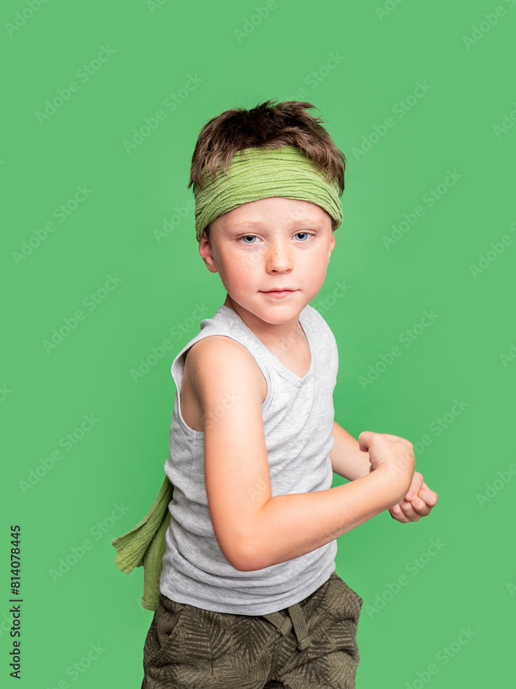Serious boy with headband in studio on green background Serious boy with headband in studio on green background