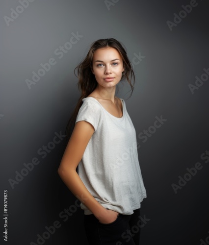 A brunette with wavy hair and a fleeting smile in light clothes on a gray background. Women's fashion and beauty, confident strong woman. © Restyler