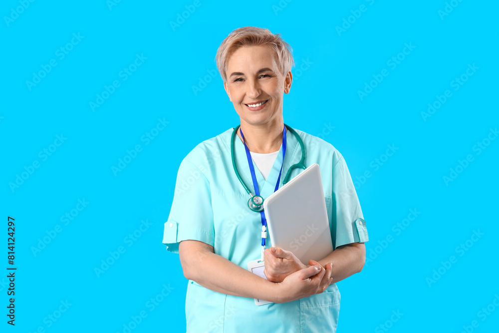 Mature female nurse with laptop on blue background Mature female nurse with laptop on blue background