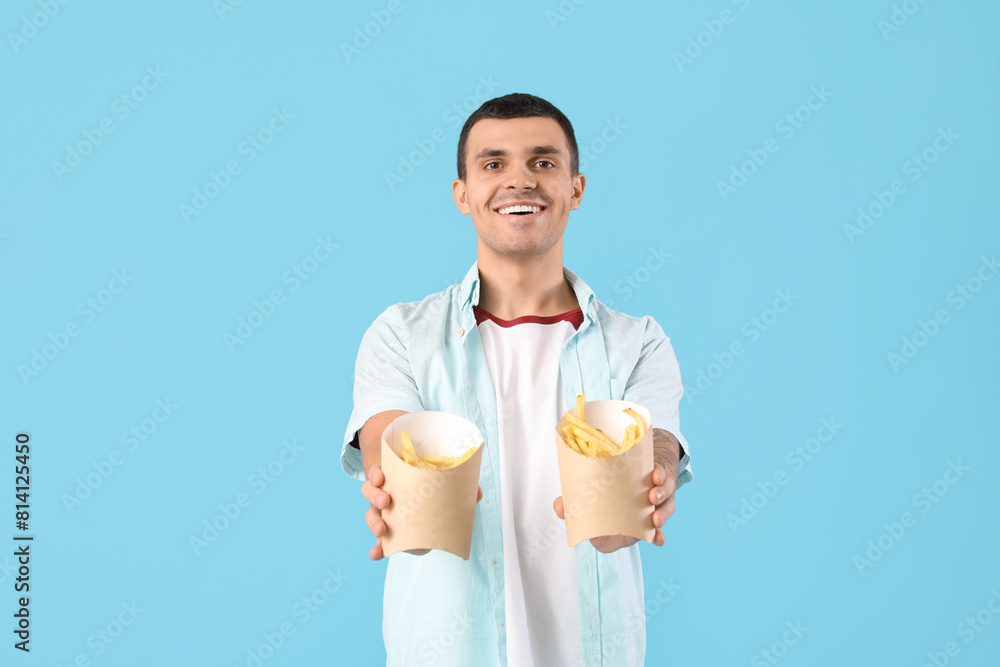 Happy young man with french fries on blue background Happy young man with french fries on blue background