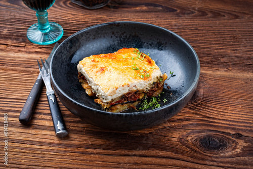 Traditional Greek moussaka with beef mince, eggplant and bechamel sauce served as close-up in a Nordic design Bowl on an old wooden board © HLPhoto