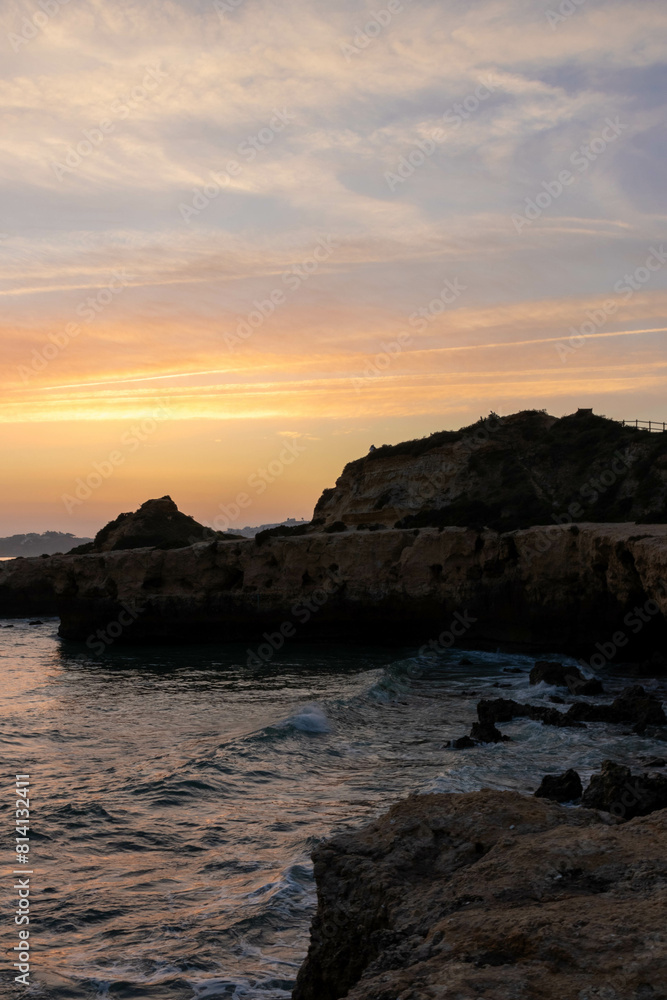 Silhouette View of a Cliffs Along the Beach with a Hazy Sunset in Albufiera Portugal Silhouette View of a Cliffs Along the Beach with a Hazy Sunset in Albufiera Portugal