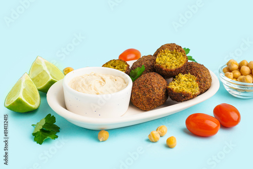 Plate with delicious falafel balls, hummus, tomatoes and chickpea on blue background