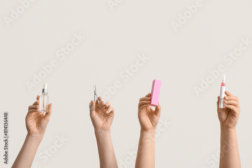 Female hands holding bottle and pen of cuticle oil, scissors with buffer on white background photo