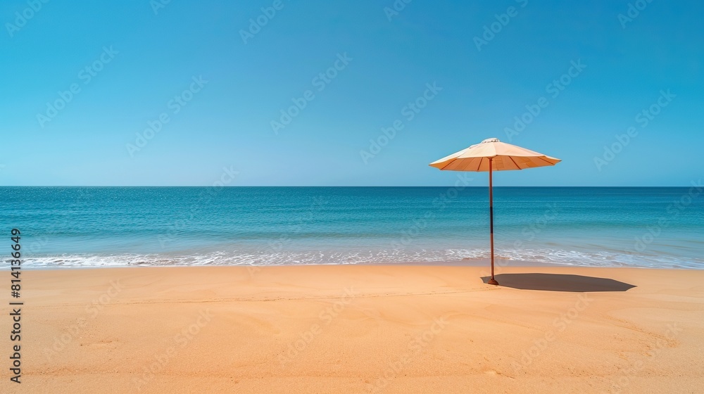Blurred beach background with straw umbrella on sandy beach and blue ocean. Relaxing summer vacation and travel concept.