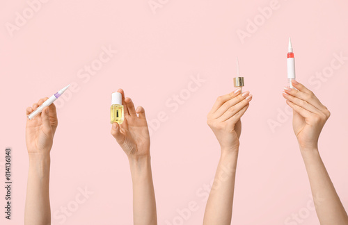 Female hands with bottle  cuticle oil pens and pipette on pink background