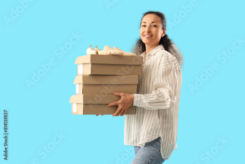 Female shoemaker with wooden shoe trees and boxes on blue background