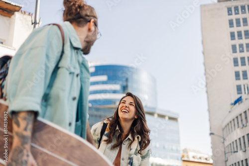 Happy alternative couple with skateboards taking a walk on urban street