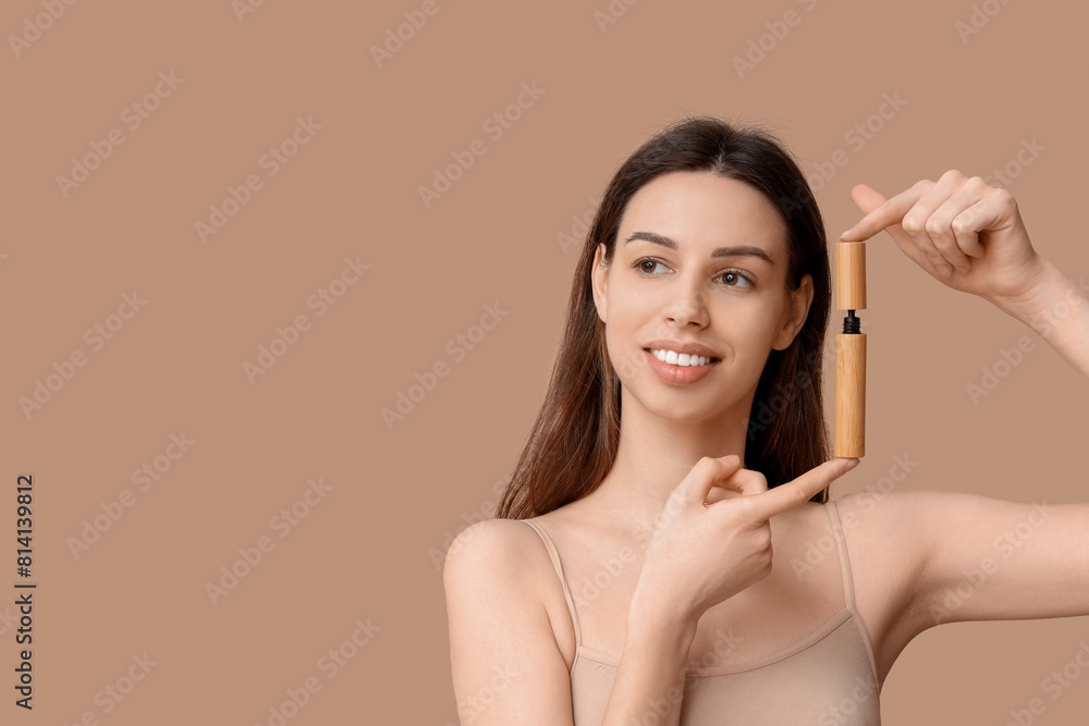 Fototapeta premium Portrait of beautiful young woman with mascara on brown background