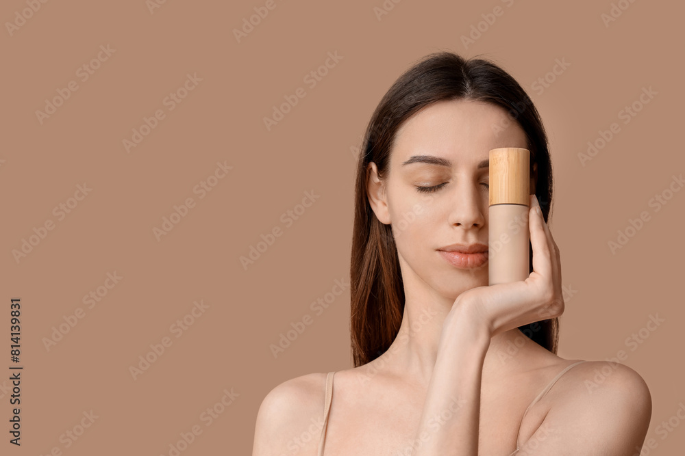 Beautiful young woman covering one eye by foundation on brown background Beautiful young woman covering one eye by foundation on brown background