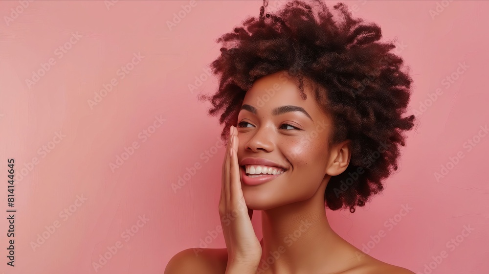 A woman with afro hair smiling against a pink background. A woman with afro hair smiling against a pink background.