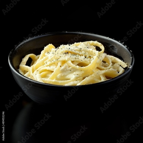   A zoomed-in image of a black plate holding a bowl of pasta and a spoon positioned in the center of it