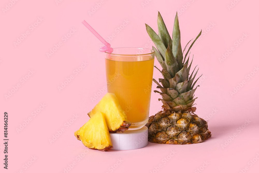 Glass of fresh pineapple juice on stand against pink background Glass of fresh pineapple juice on stand against pink background