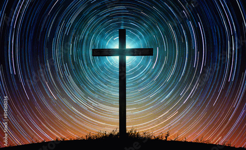 The silhouette of the cross as a symbol of the Christian religion against the background of the night sky with tracks of stars. Concept on the theme of God, paradise, religion, Christian faith. 