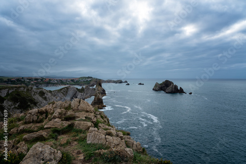 A rocky shoreline with a cloudy sky and a body of water, Costa Quebrada, Urros de Liencres, Cantabria, Spain.