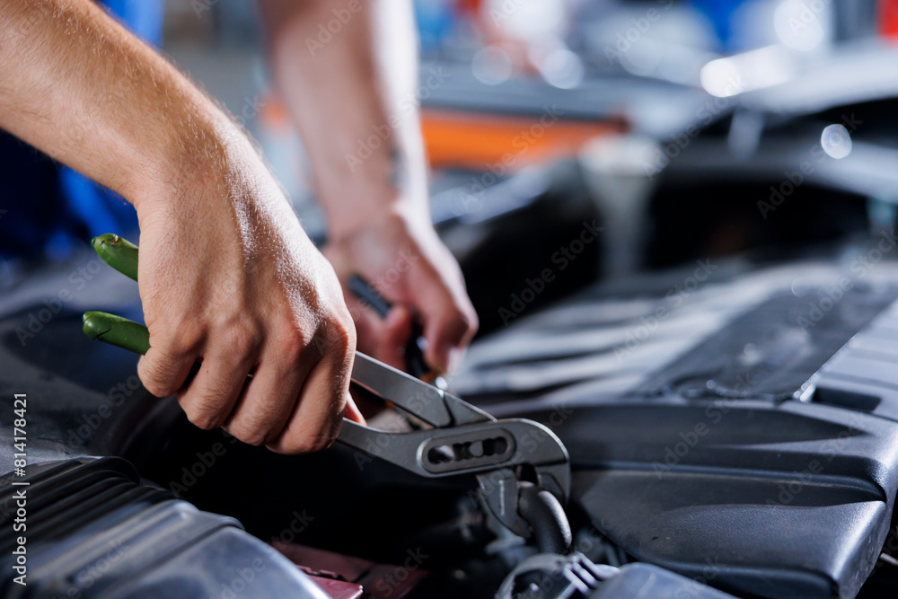 Car service technician expertly examines engine using advanced mechanical tools, ensuring ideal automotive performance and safety. Meticulous garage expert conducts routine vehicle checkup with pliers Car service technician expertly examines engine using advanced mechanical tools, ensuring ideal automotive performance and safety. Meticulous garage expert conducts routine vehicle checkup with pliers