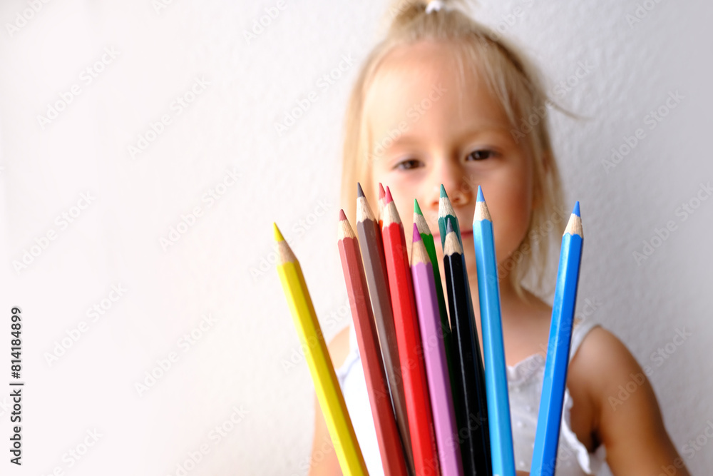 small child, blonde girl holds joyfully a bunch of colored pencils, concept of parenting, student writing supplies, back to school, names colors, drawing, learning to draw small child, blonde girl holds joyfully a bunch of colored pencils, concept of parenting, student writing supplies, back to school, names colors, drawing, learning to draw