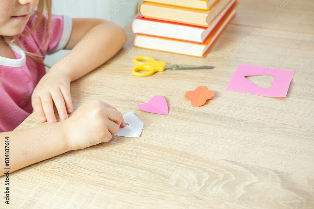 preschooler girl practicing scissor skills by cutting out shapes such house, heart and flowers for applique from colored paper preschooler girl practicing scissor skills by cutting out shapes such house, heart and flowers for applique from colored paper