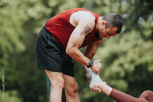 Fit man assists his girlfriend who hurt her leg while running, providing care and support in a shaded park.