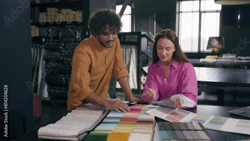 Diverse fashion designers Arabian man Caucasian woman couple customers choosing fabric samples talk discuss interior design salesman help to choose swatches colors material cloth in tailoring atelier
