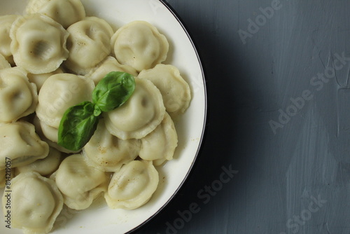 Cooked boiled dumplings in a bowl of basil greens top view close-up on a gray background with space for text copyspace