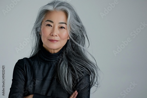 Mature asian white-haired woman posing with her arms crossed isolated over grey background