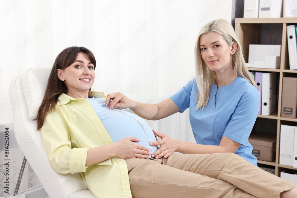 Pregnancy checkup. Doctor measuring patient's tummy in clinic Pregnancy checkup. Doctor measuring patient's tummy in clinic