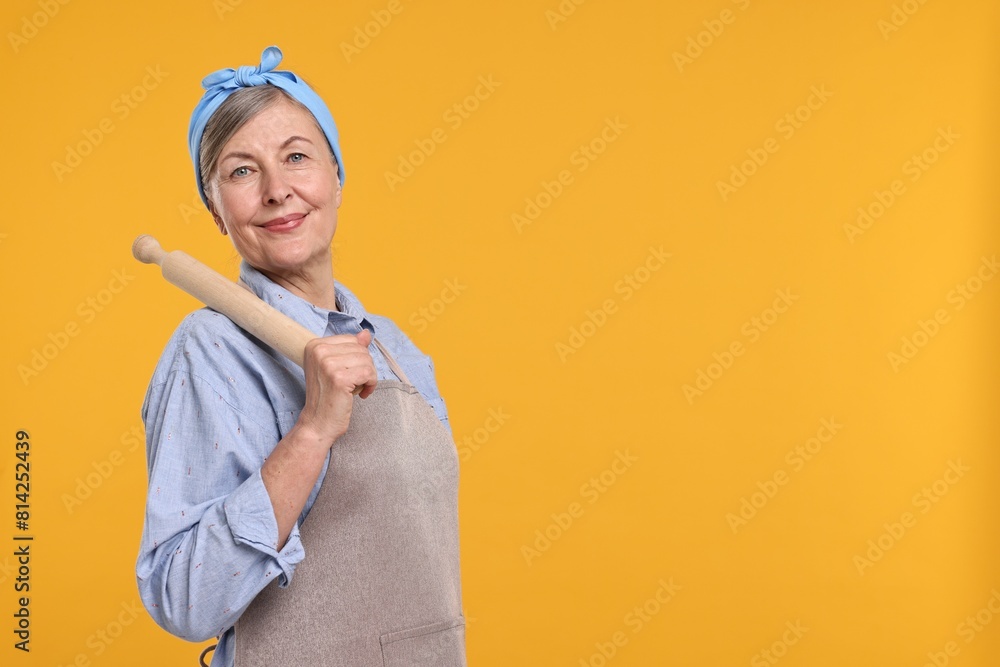 Happy housewife with rolling pin on orange background, space for text Happy housewife with rolling pin on orange background, space for text
