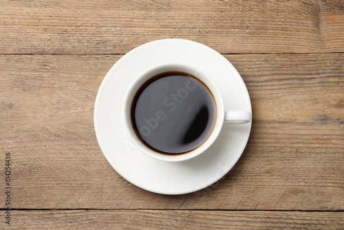 Cup of aromatic coffee on wooden table, top view