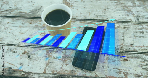 Image of arrow on growing graph over coffee cup and cellphone on wooden table