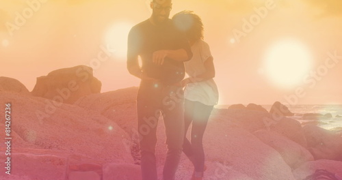 Image of light spots over biracial couple at beach
