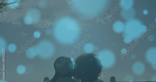 Image of light spots over biracial couple kissing