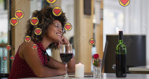 Image of hearts over african american woman drinking wine and having image call