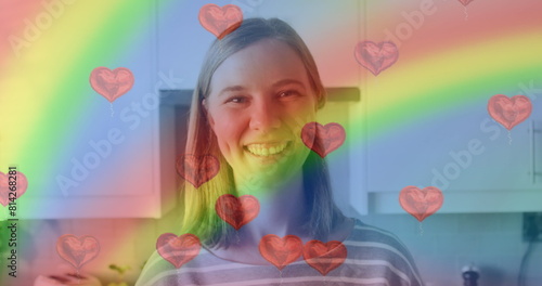 Image of heart emojis and rainbow flag over caucasian woman smiling