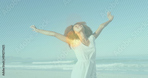 Image of striped patterns over biracial young woman with arms outstretched spinning at beach