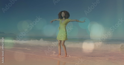 An african american woman is happy on a tropical beach, raising her hands and smiling in slow motion
