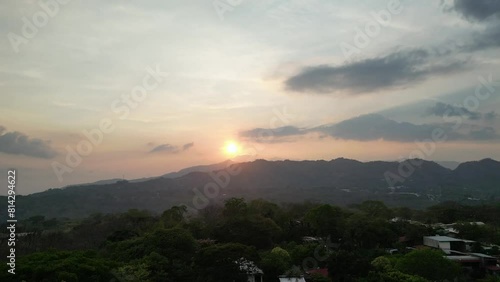 Drone Shot Rising Over Tree in Foreground Revealing Sunset Over Alajuela Countryside photo