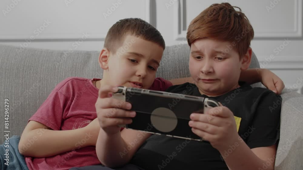 A small younger brother watching how his brother playing handheld console. Two boys enjoying videogames together in living room. Free time spending of modern kids. Unlucky in this round, try again A small younger brother watching how his brother playing handheld console. Two boys enjoying videogames together in living room. Free time spending of modern kids. Unlucky in this round, try again