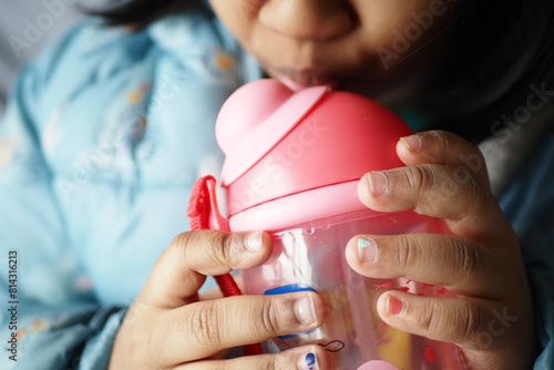 child girl drinking water sitting on sofa